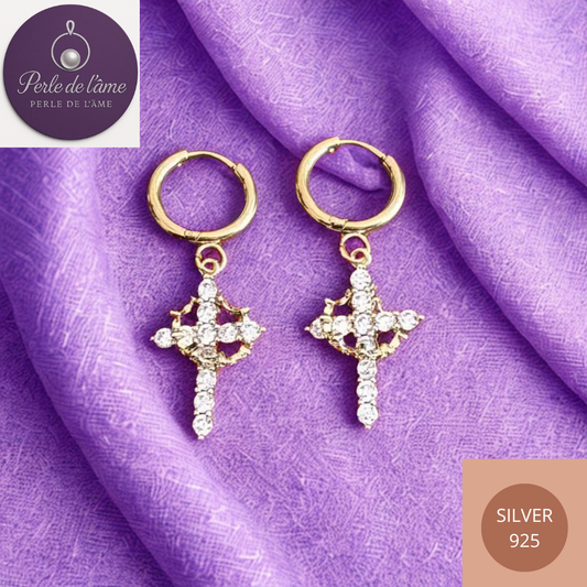 Boucles d'oreilles avec croix dorée.